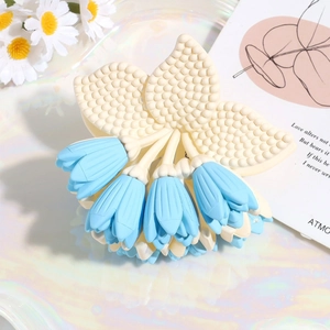 Detalle de una pinza para el pelo con flor azul claro y textura mate sobre fondo crema