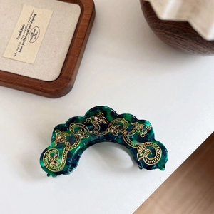 Detail of green marble acetate hair claw with golden filigree and pink rhinestones
