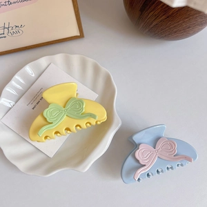 Cute bow shark hair clips in yellow-green and blue-pink color blocks on shell tray