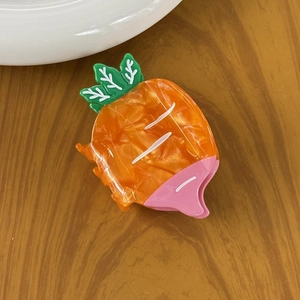 Detail of creative carrot-shaped hair claw made from glossy acetate with leaf accents