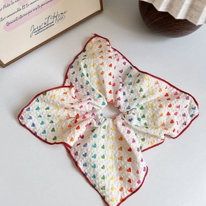 Dettaglio dell'elastico scrunchie con cuori colorati, cuciture rosse e tessuto bubble