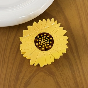 Elegant sunflower acetate hair claw clip with yellow petals on a dark wood background