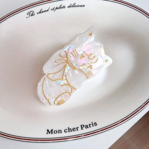 Détail macro de la pince à cheveux chat en acétate blanc irisé avec gravures dorées