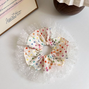 Dettaglio di un elastico bianco con cuori colorati e bordo in rete a pois fini