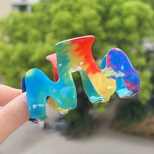Gros plan d'une pince à cheveux arc-en-ciel en forme de M tenue à l'extérieur