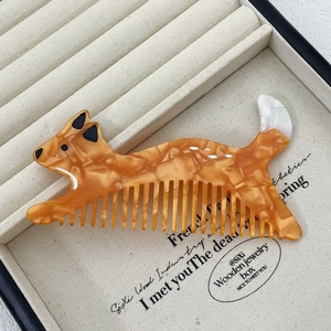 Detailed view of dog-shaped acetate comb with amber texture on jewelry tray