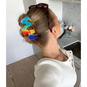 Pince à cheveux arc-en-ciel ondulée portée par un mannequin dans un décor moderne