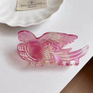 Detailed side view of pink bird-shaped acetate hair claw clip on a white decorative plate