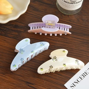 Three premium floral cellulose acetate hair claws in pastel blue, purple, and cream colors