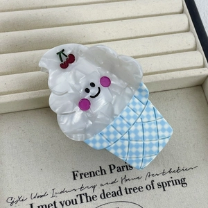 Détail d'une pince à cheveux en forme de glace avec cerise et motif à carreaux bleus