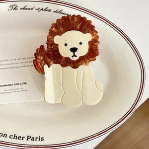 Détail de la pince à cheveux lion en acétate sur une assiette décorative blanche