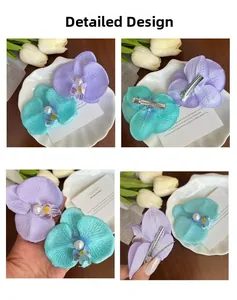 Detail view of orchid hair clips showing fabric texture and pearl center on wooden table