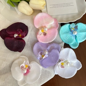 Elegant set of six colorful butterfly orchid hair clips with pearls on a soft mesh background