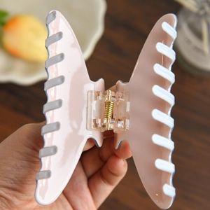 Detail of a large pink acetate claw clip with white accents and a strong metal spring