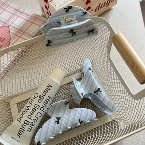 Set of three blue striped hair claws with black bow patterns in a decorative metal basket