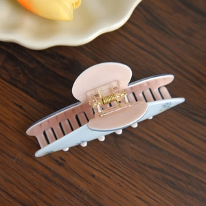 Detailed top view of large acetate hair claw clip with blue floral pattern and gold spring