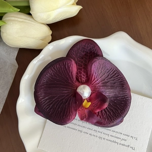 Close-up of dark purple orchid hair clip with realistic fabric texture and pearl center