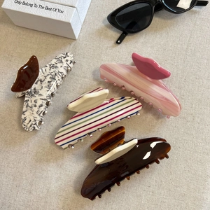 Set of four stylish acetate hair claws with marble and striped patterns on linen cloth