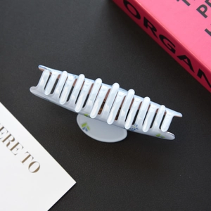 Macro detail of large light blue floral acetic acid hair claw clip on black background