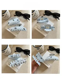 Close-up of blue striped acetate hair claw clip with elegant black bow pattern details