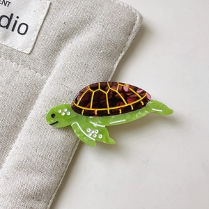 Détail d'une pince à cheveux tortue verte en acétate avec motif de carapace ambre poli