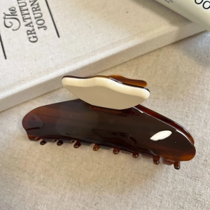 Macro shot of large amber acetate hair claw clip with white butterfly motif detail