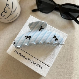 Detail of blue striped hair claw clip with black bow patterns and multi-tooth design