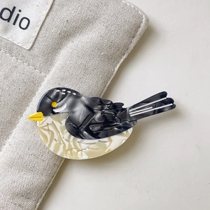 Détail d'une pince à cheveux en forme d'oiseau en acétate avec textures marbre et fleurs