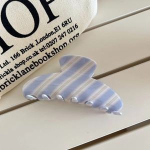 Détail d'une pince à cheveux à rayures bleues et crème pour coiffure avec finition polie