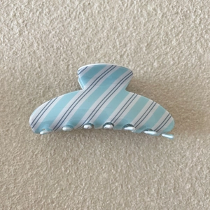 Vue détaillée d'une pince à cheveux à rayures bleu clair avec une finition en acrylique poli