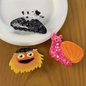 Cute acetate hair claws featuring snail, bear, and monster designs on a white plate