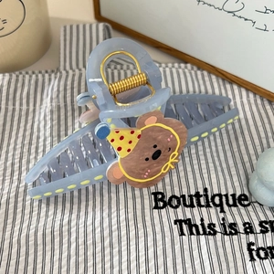 Detail van lichtblauwe haarklem met cartoonbeer en een sterke gouden metalen veerclip
