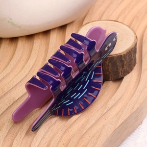 Détail d'une pince à cheveux violette en forme de chat avec des rayures colorées