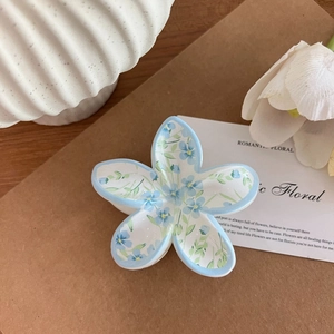 Detailansicht der hellblauen Haarklammer mit Blumenmuster auf rustikalem Packpapier