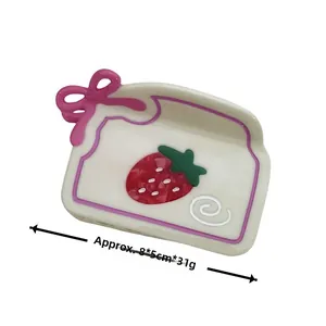 Dettaglio della molletta per capelli in acetato crema con fiocco rosa e fragole
