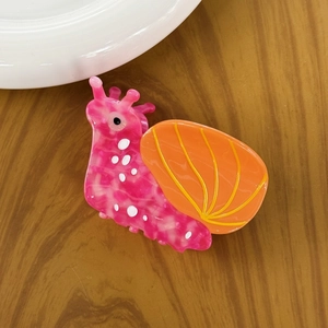 Top view of a cute snail-shaped hair claw clip in pink and orange acetate finish