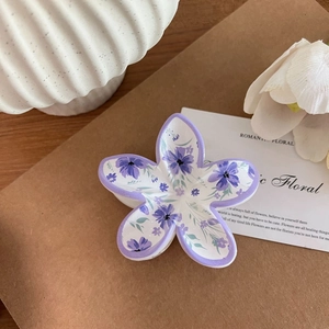 Detail einer lila geblümten Frangipani Haarklammer auf rustikalem Hintergrund