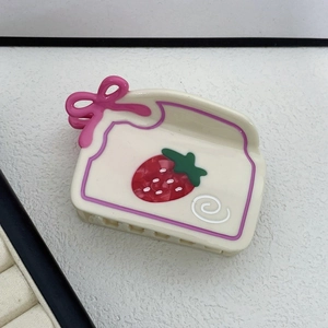 Dettaglio di un fermaglio per capelli in acetato bianco crema con fiocco rosa e fragole