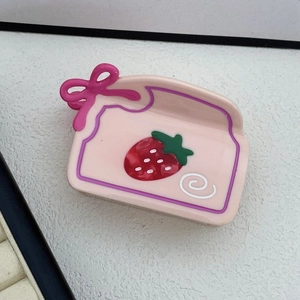 Dettaglio molletta per capelli a fragola rosa con fiocco rosso in acetato