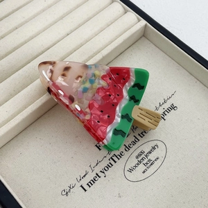 Detail view of a creative watermelon claw clip made of acetate on a textile tray