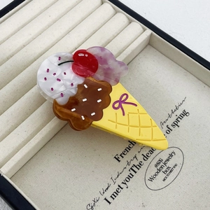 Macro detail of ice cream cone hair claw clip with colorful resin layers in jewelry box