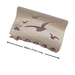 Detail of cream acetate shark hair claw with seagull cutout design and 8x5cm dimensions