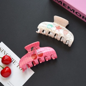 Vue détaillée de pinces à cheveux à carreaux cerise et motif coquillage en acrylique
