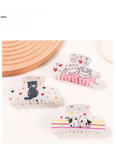 Détail de trois pinces à cheveux crème avec des motifs mignons de chats et de cœurs