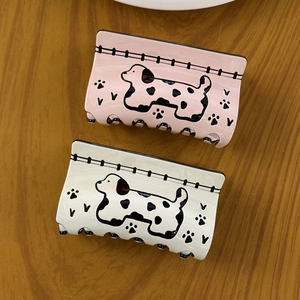 Pink and white acetate shark hair claws with dalmatian dog patterns on a wooden table