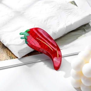 Macro detail of a red chili-shaped hair claw clip made of glossy acetate material