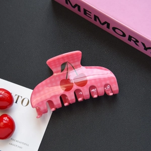 Détail d'une pince à cheveux à carreaux roses avec motif cerise sur fond en cuir