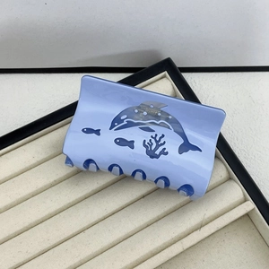 Detail of light blue acetate hair claw clip featuring dark blue sea creature patterns
