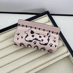 Close-up of a pink acetate shark hair clip featuring cartoon dalmatian and paw patterns