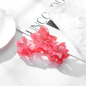 Gros plan sur une pince à cheveux fleurie en acétate rose marbré avec des strass